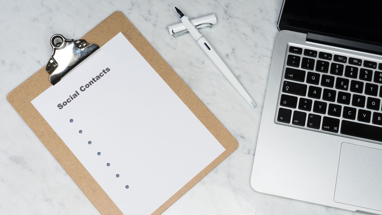 A clipboard with a short checklist sits beside a laptop and pen on a desk.