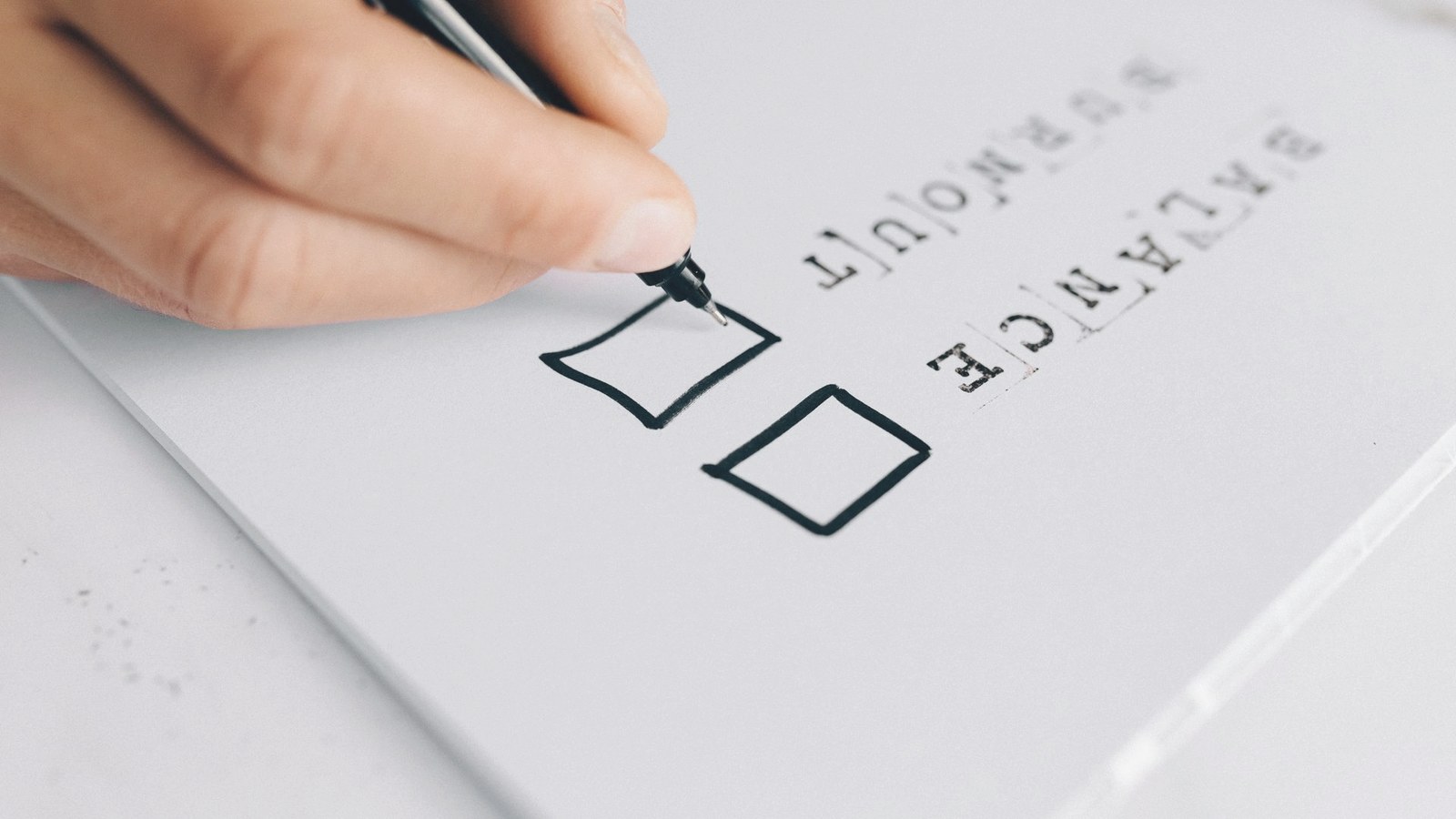 Close-up of a hand marking boxes on a paper checklist.